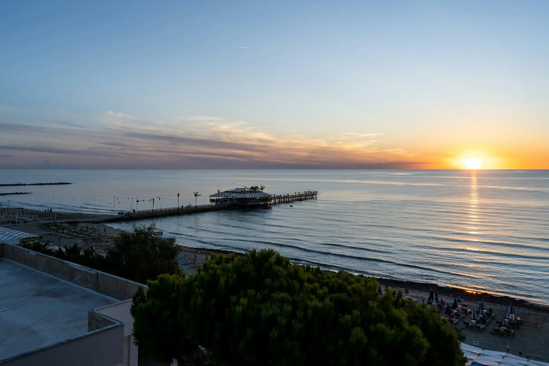 Soluppgång över Adriatiska havet vid Durrës med en lång pir ut i det stilla vattnet