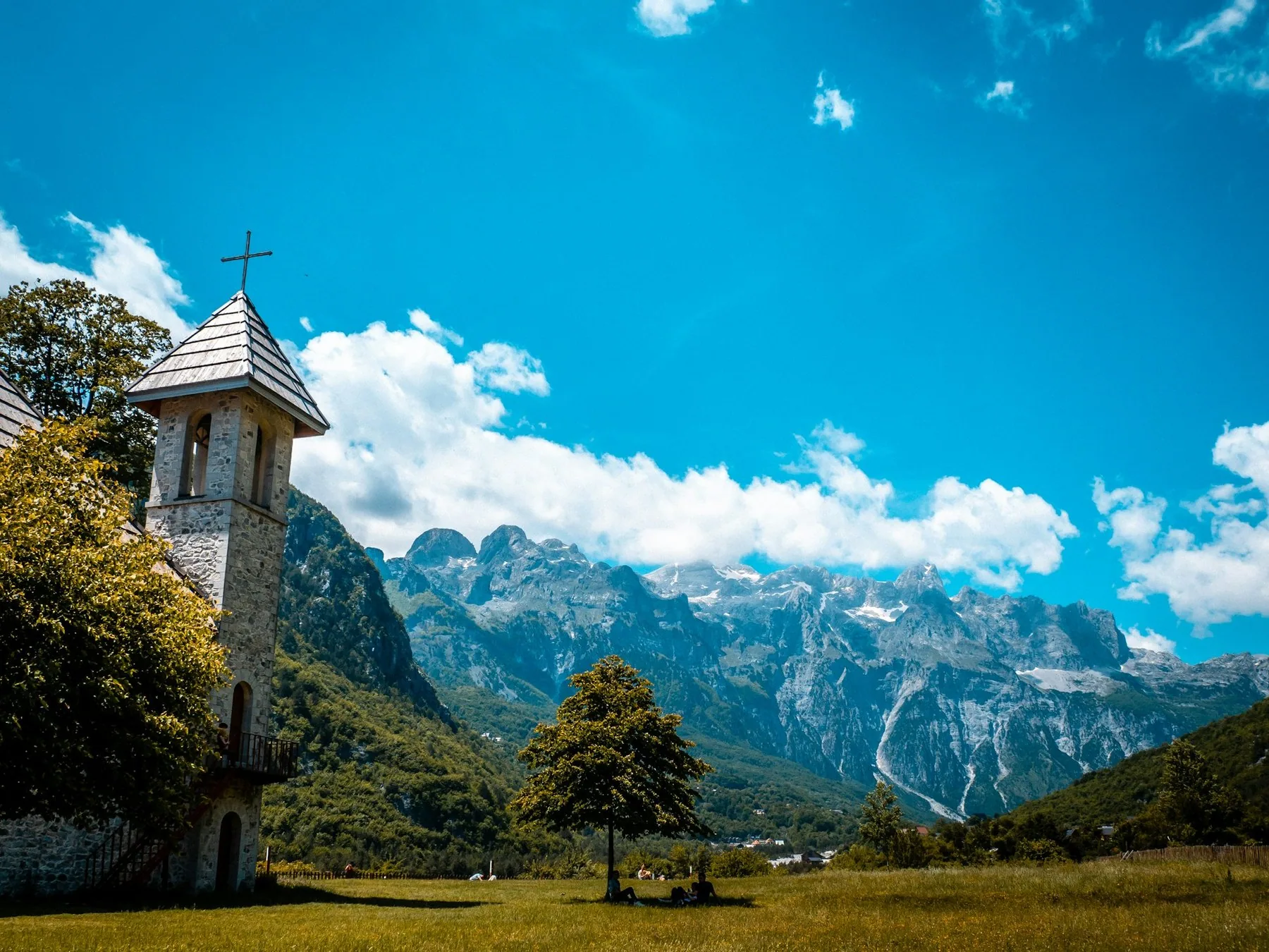 Thethkyrkans stentorn framför de taggiga, delvis snöklädda Albanska alperna under blå himmel