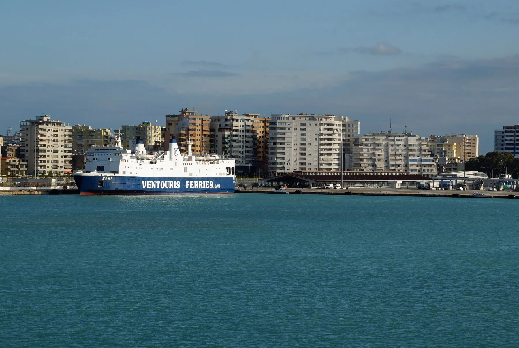 Passagerarfärja vid kaj i Durrës hamn med stadens bostadshus bakom
