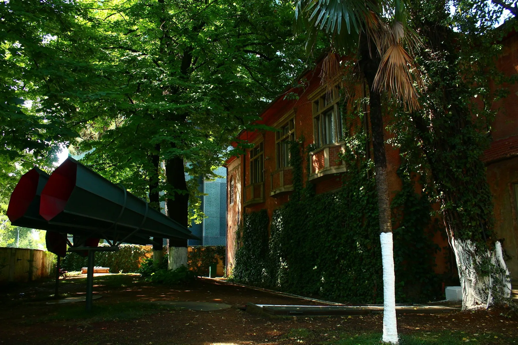 Röda högtalarhorn framför den murgrönsklädda tegelbyggnaden House of Leaves i Tirana