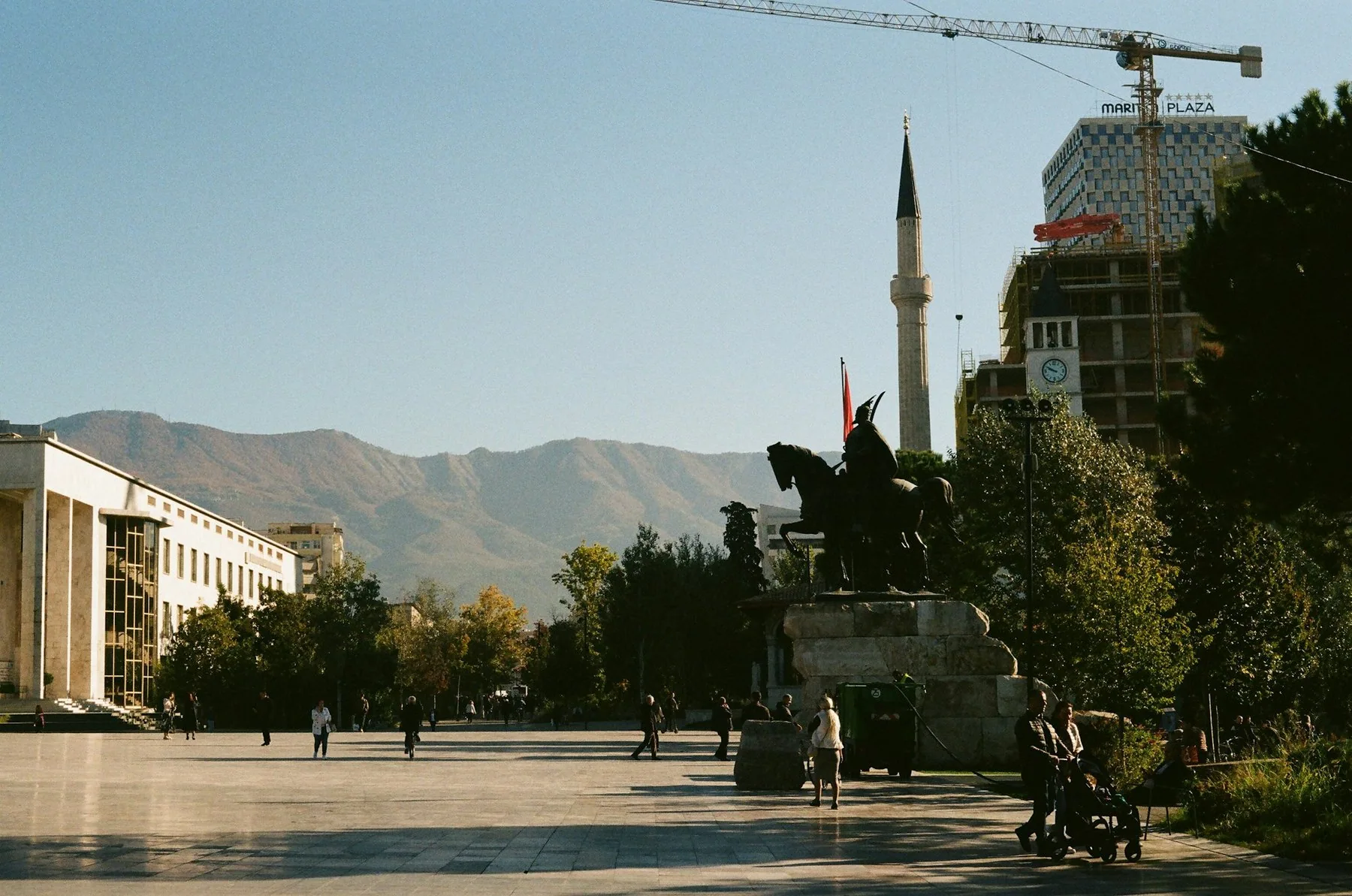 Ryttarstatyn av Skanderbeg på torget i Tirana, med en minaret och gröna berg i bakgrunden